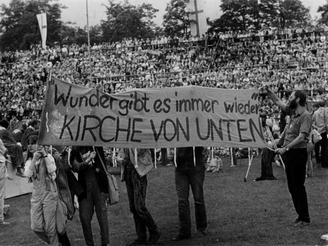 Beim Kirchentag 1987 halten Vertreter:innen der "Kirche von unten" Plakate, hier: "Wunder gibt es immer wieder. Kirche von unten"