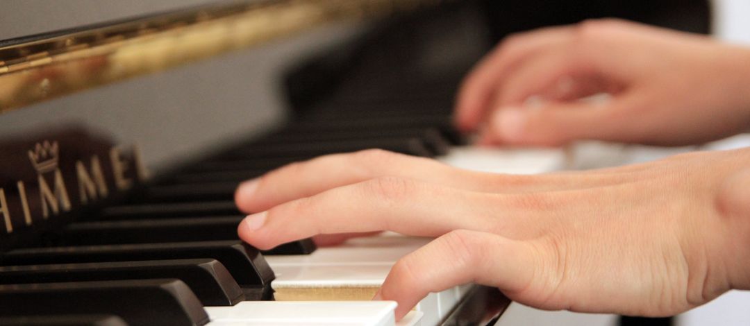 Eine Studentin spielt im Andachtsraum der theologischen Fakultät Klavier. Man sieht ihre Hände auf der Klaviatur.
