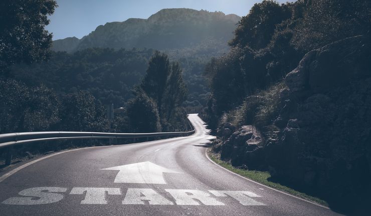 Eine Straße führt in die Berge, auf ihr das Wort "Start".