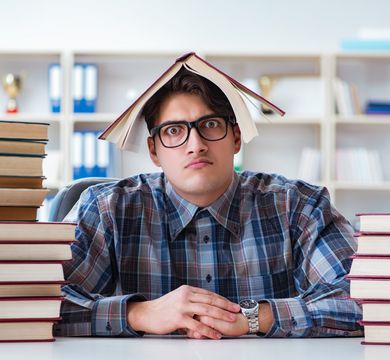 Mann zwischen Bücherstapeln (Quelle: Colourbox)