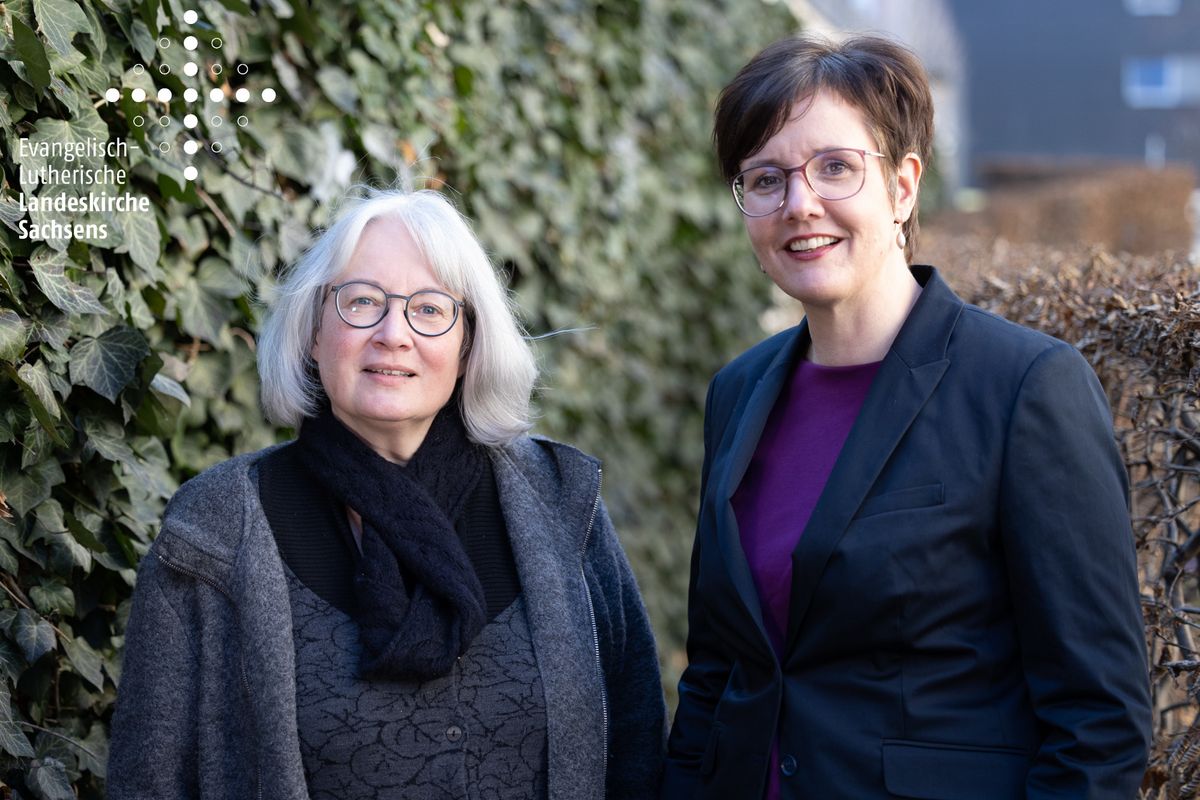 Zwei Frauen vor grünem Hintergrund, Gabriele Mendt und Astrid Reglitz mit Logo der Sächsischen Landeskirche, Foto: EvLKS.