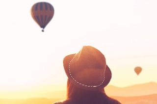 Foto: Frau mit Hut schaut Heißluftballons hinterher colourbox.de