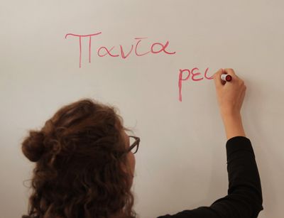 Eine Studentin schreibt an einem Whiteboard mit einem roten Stift. Dort stehen die Worte panta rei. Das ist Altgriechisch und heißt alles fließt.