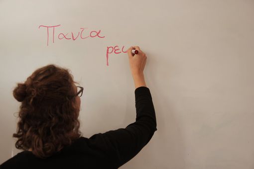 Eine Studentin schreibt an einem Whiteboard mit einem roten Stift. Dort stehen die Worte panta rei. Das ist Altgriechisch und heißt alles fließt.