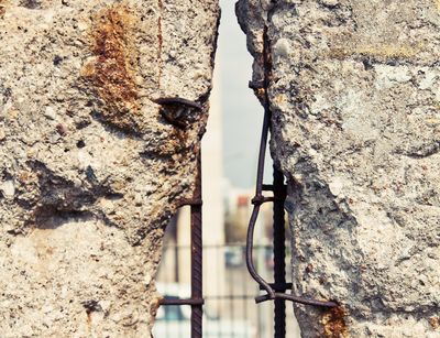 Das Foto zeigt ein Stück von der Berliner Mauer. In der Mauer ist ein Loch geschlagen. Auf der anderen Seite sieht man die Rückseite eines alten Autos.