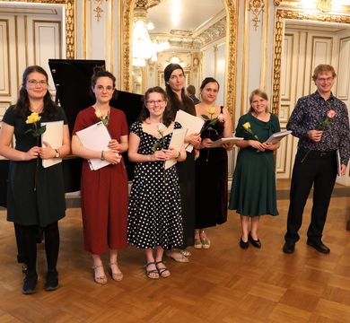 07_23_Absolventen_Theol Die Absolvent:innen der Ersten Theologischen Prüfung und der Diplomprüfung stehen nebeneienander und halten ihre Zeugnisse in der Hand.