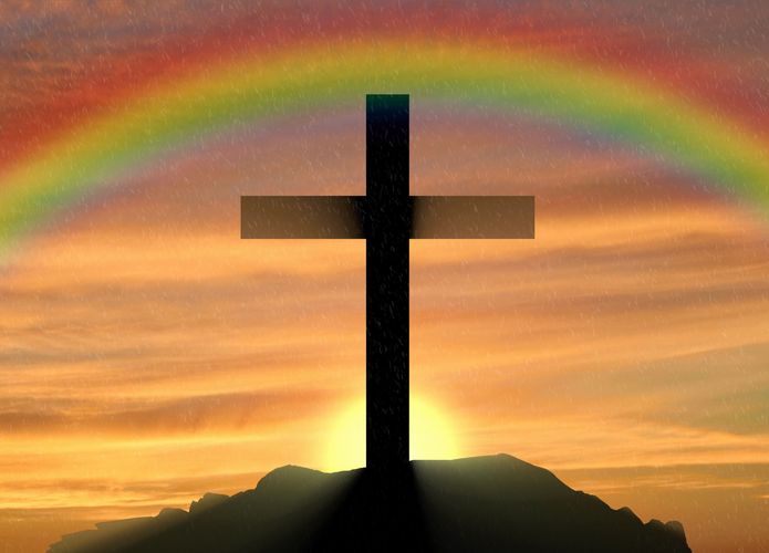 Kreuz auf einem Berg, im Hintergrund Regenbogen